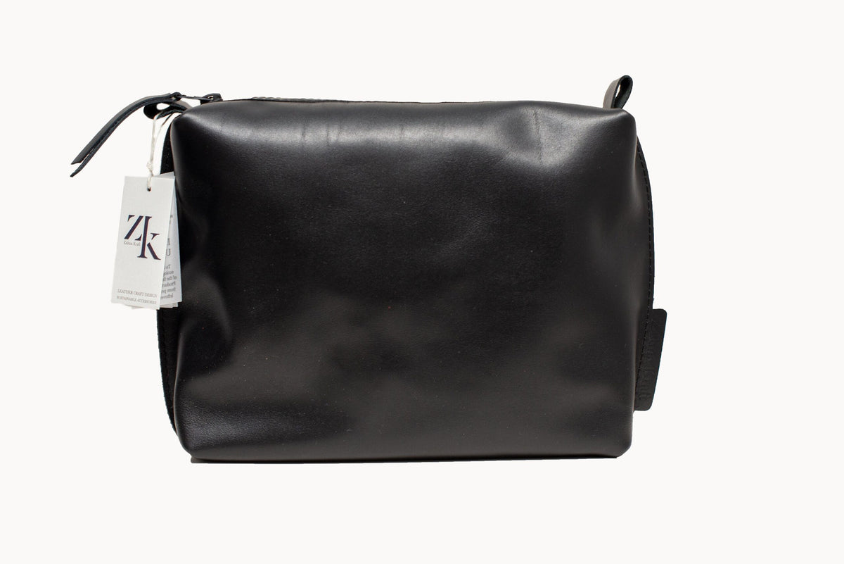 Large black leather Zelma Kraft cosmetic bag on white background, front view with a ZK hang tag at the zip.