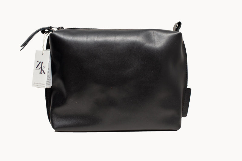 Large black leather Zelma Kraft cosmetic bag on white background, front view with a ZK hang tag at the zip.