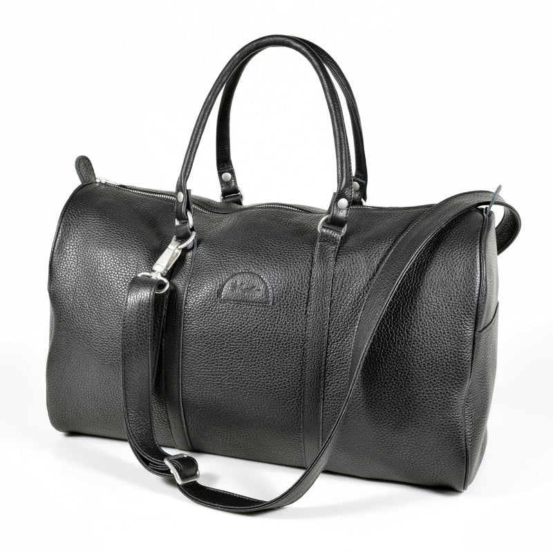 Black leather Papillon travel bag on white background, three-quarter view with top handles and shoulder strap.